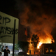 “RIP Rayshard” is spray painted on a sign as as flames engulf a Wendy’s restaurant during protests Saturday, June 13, 2020, in Atlanta.
